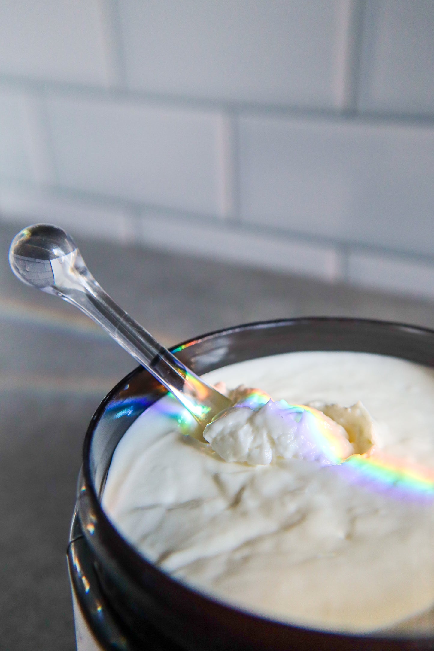 Spoonful of creamy body butter in a container with a blurred background