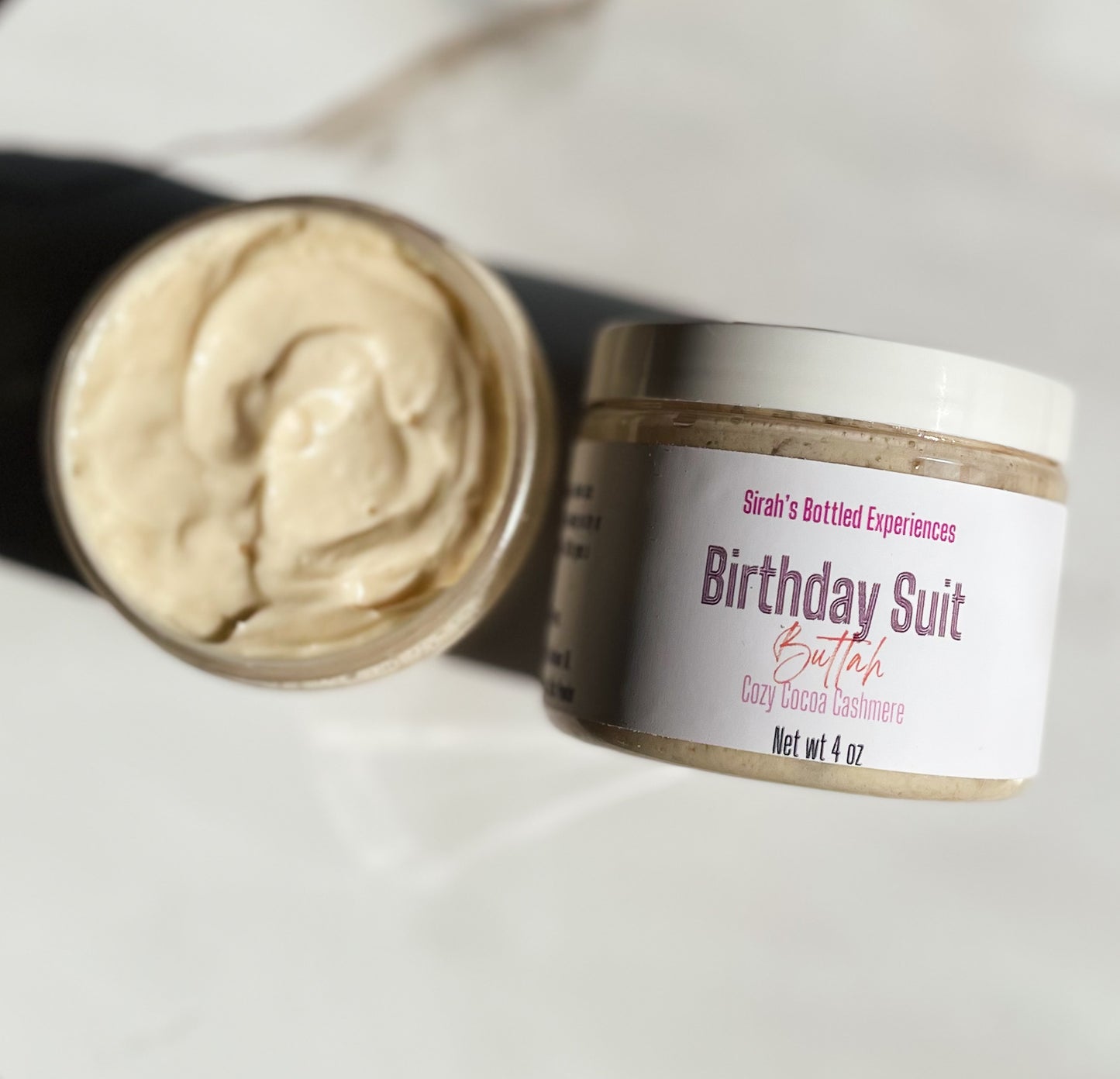 Jar of 'Birthday Suit Butter' with a visible label on a light background